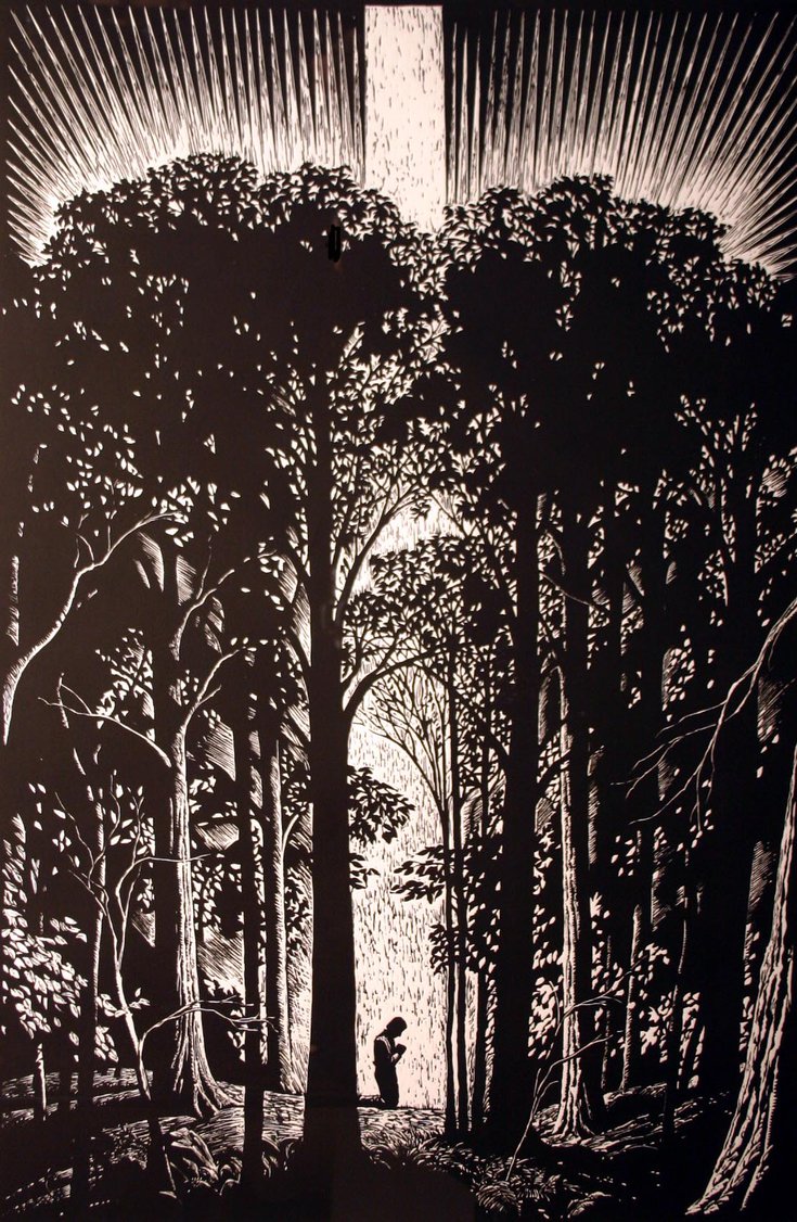 A individual kneeling in the woods.