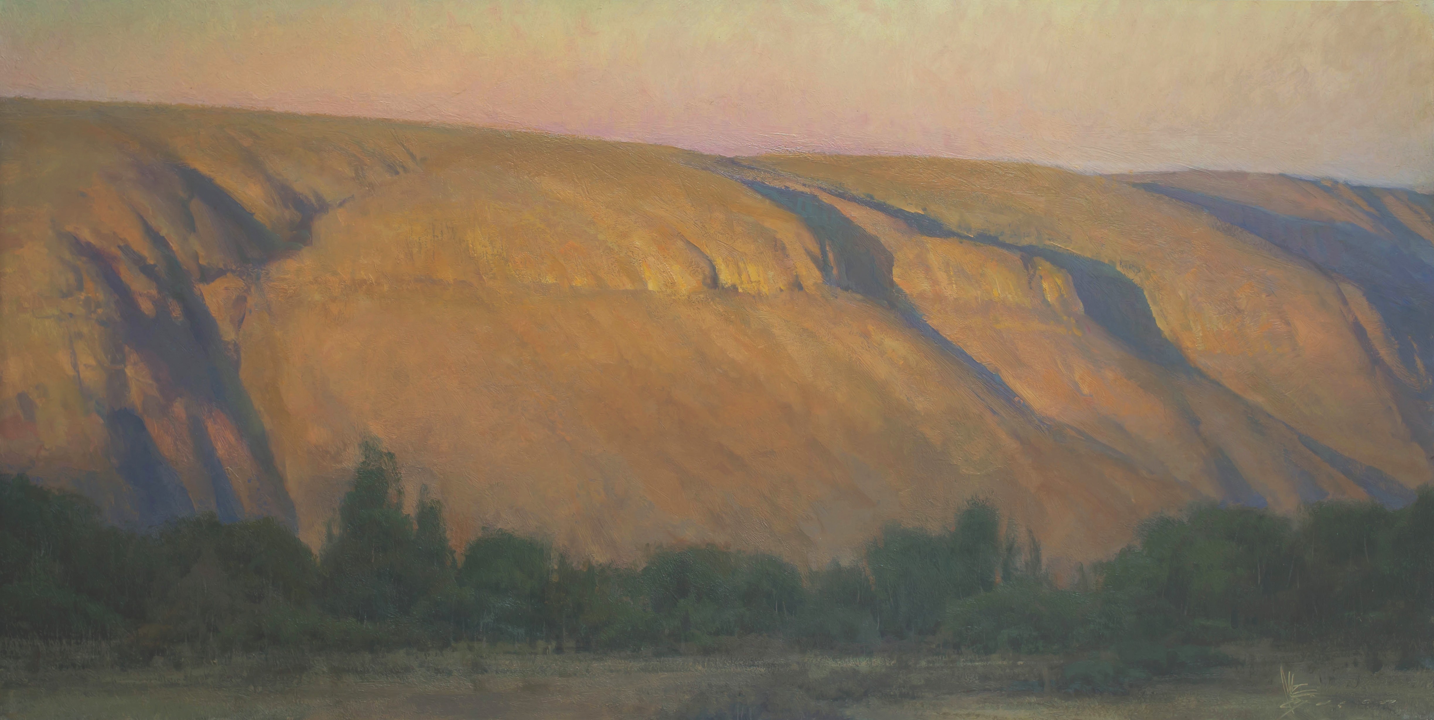 Sunlit cliffs near Bear River Crossing in Wyoming. There are trees at the base of the bluffs.