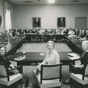 En 1962. Con las miembros de la presidencia presidiendo la mesa (izquierda a derecha: Madsen, Spafford y Sharp), la Mesa Directiva General de la Sociedad de Socorro posa en el Edificio de la Sociedad de Socorro, que tiene seis años de construido. Las miembros de la Mesa Directiva capacitaban a las Sociedades de Socorro de las unidades en todo el mundo, supervisaban la producción de la ropa de templo, publicaban la revista <i>Relief Society Magazine,</i> y elaboraban el curso de estudio de la Sociedad de Socorro.