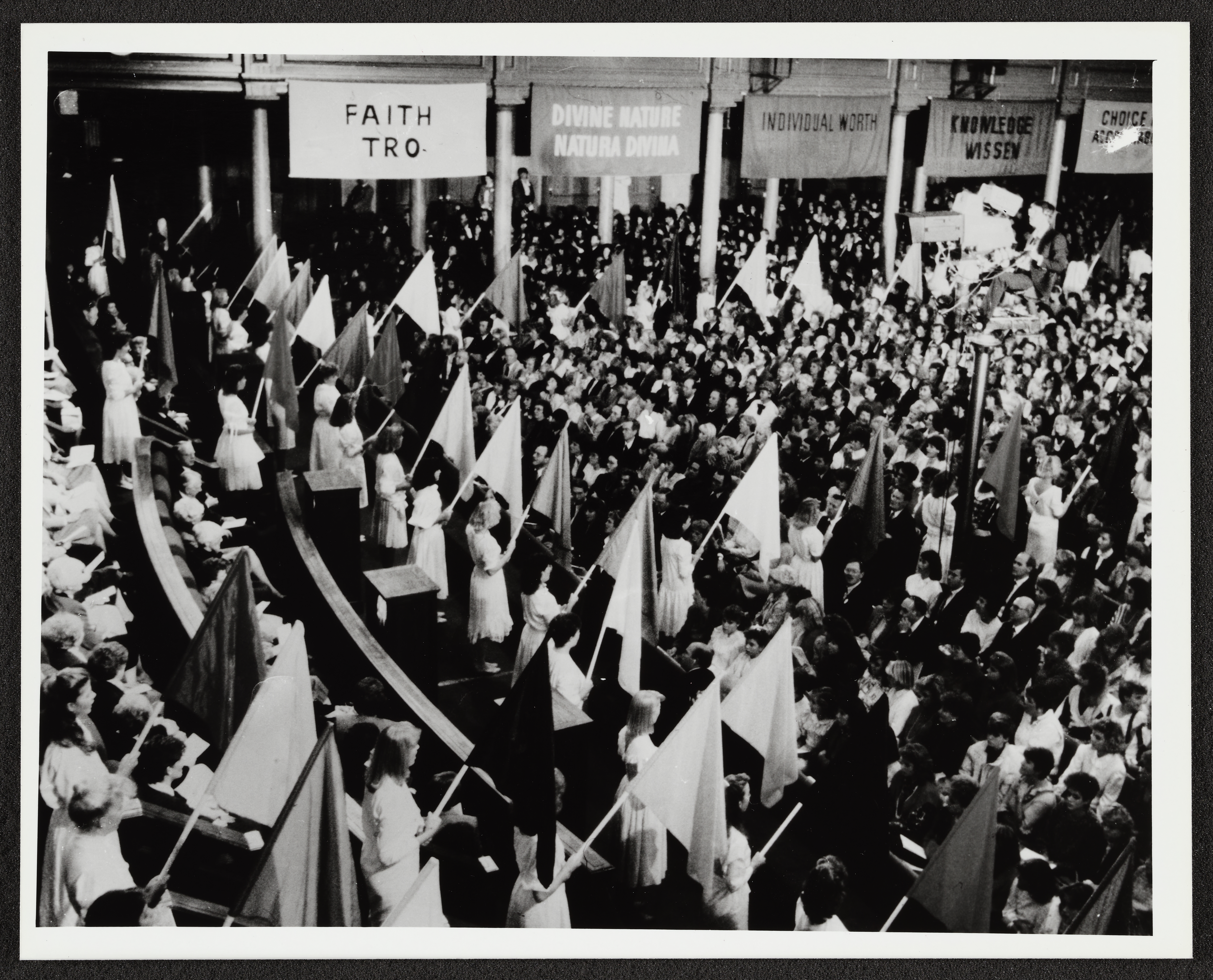 <strong>Young Women fireside and worldwide satellite broadcast.</strong> 1985. In the fireside, Ardeth Greene Kapp and her presidency introduced the Young Women theme and values. Music at the fireside brought together new changes and past traditions as young women sang Ruth May Fox’s 1930 MIA anthem, “Carry On,” while holding aloft flags with colors representing each of the new values. (Image courtesy <em>Church News</em>, copy at Church History Library, Salt Lake City.)