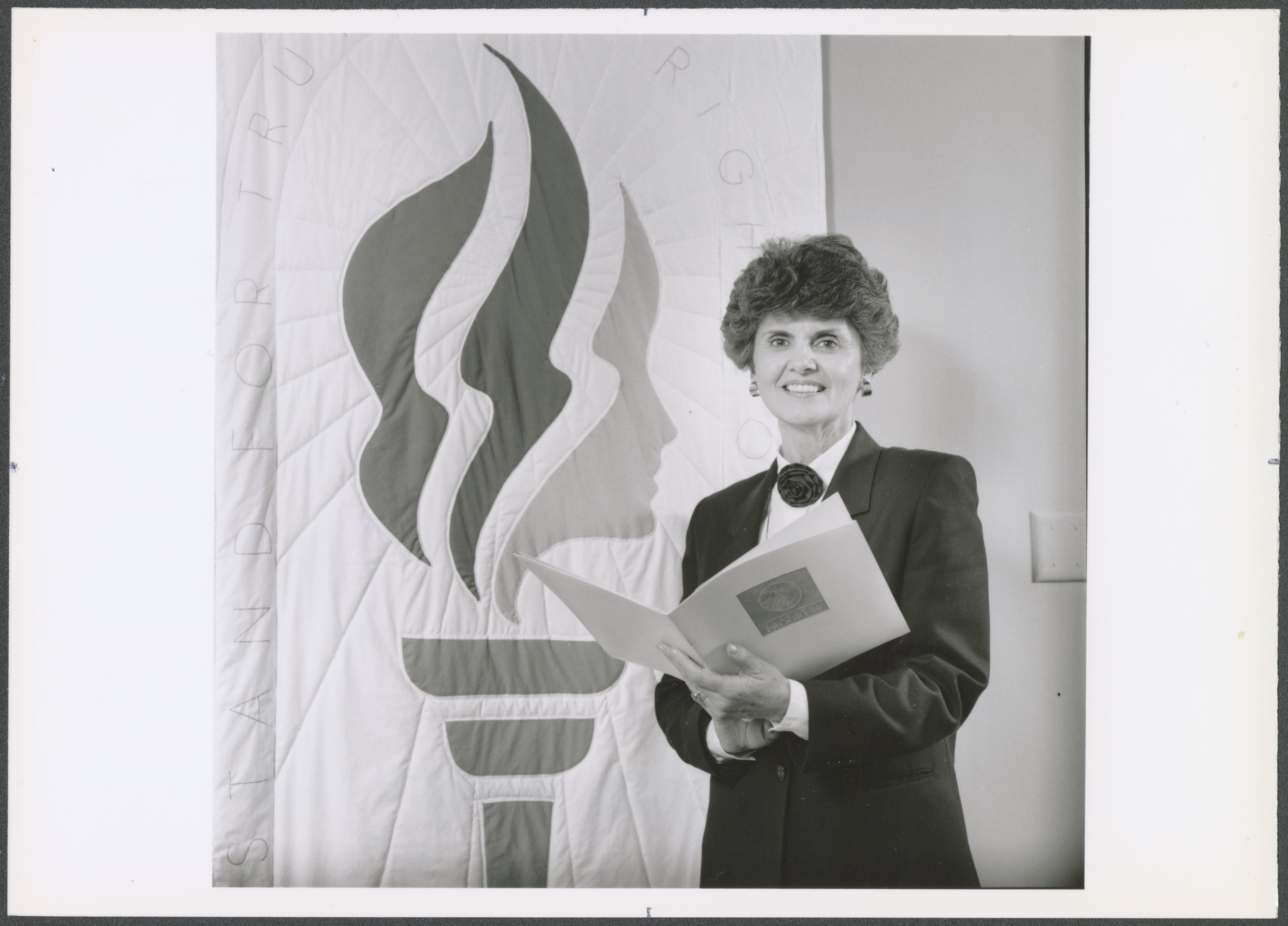 <strong>Ardeth Greene Kapp with Young Women logo and Personal Progress booklet.</strong> 1989. During her tenure from 1984 to 1992, Kapp reoriented the Young Women programs around a theme and values expressing Latter-day Saint beliefs. The torch logo and revised Personal Progress achievement program further solidified the organization’s identity after rapid changes in the 1970s. (Image courtesy Church History Library, Salt Lake City.)